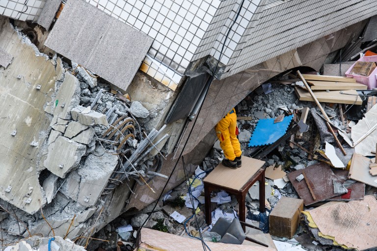 TAIWAN. A rescue worker clears debris to make way for the recovery of the dead bodies of a Hong Kong Canadian couple from the Yun Tsui building, in the Taiwanese city of Hualien on February 9, 2018. Photo by Anthony Wallace/AFP 