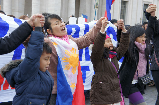 HOLDING HANDS. A Filipina wrapped in the country's flag and children hold hands in prayer 