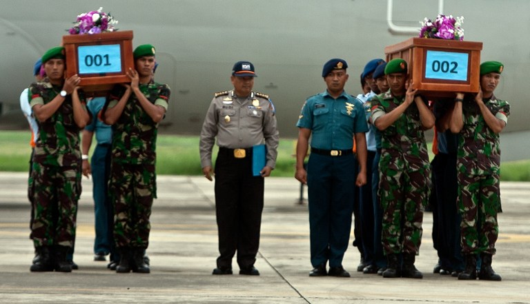 Indonesian military personnel carry coffins of victims upon their arrival at the military airbase in Surabaya on December 31, 2014.  Photo by AFP