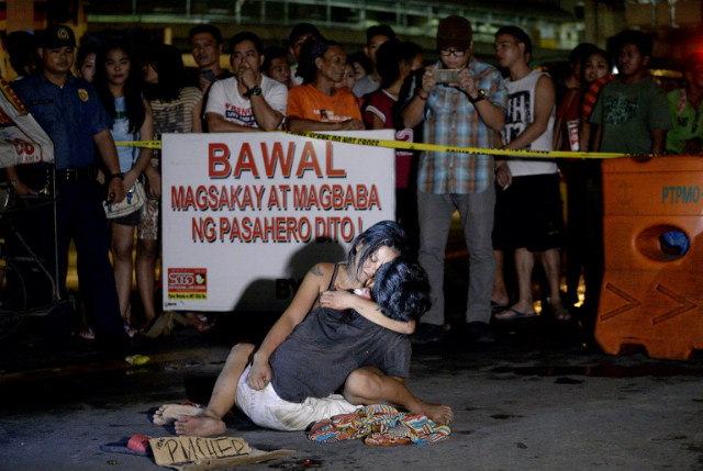 PIETA. A woman hugs her husband who was shot dead by an unidentififed gunman in Manila on July 23, 2016. The man lies next to a placard that reads, 'I'm a pusher.' Photo by Noel Celis/AFP 