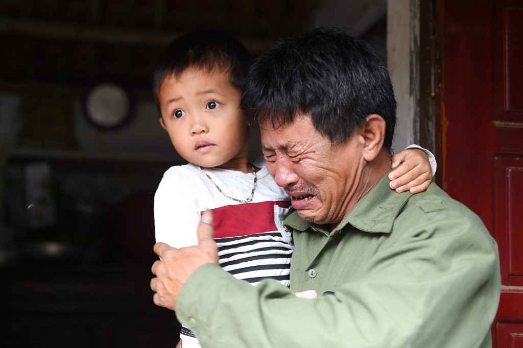 HEARTBREAK. Le Minh Tuan, father of 30-year old Le Van Ha, who is feared to be among the 39 people found dead in a truck in Britain, cries while holding Ha's son outside their house in Vietnam's Nghe An province on October 27, 2019. Photo by 
Nhac Nguyen/AFP  