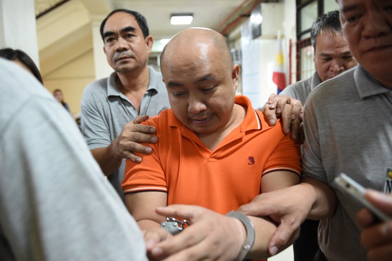 EXTRADITION. Filipino doctor Russell Salic (in orange) is escorted by National Bureau of Investigation (NBI) agents following a court hearing in Manila on November 7, 2017. Photo by Ted Aljibe/AFP 