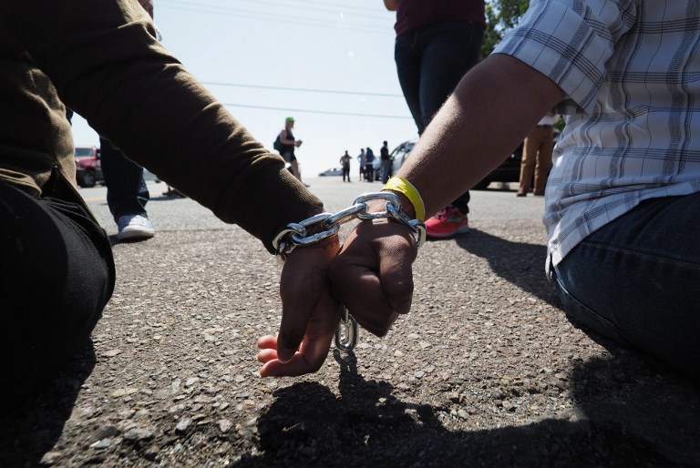 DETENTION. Protestors chained together at the wrist block traffic from passing on the road to the Otay Mesa Detention Center during a demonstration against US immigration policy that separates children from parents, in San Diego, California on June 23, 2018. Photo by Robyn Beck/AFP 