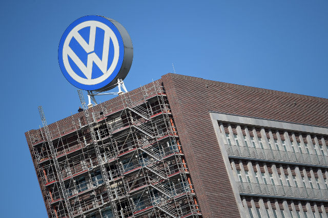 VOLKSWAGEN SCANDAL. An employee looks through a pair of binoculars as he stands next to a corporate logo of Volkswagen (VW) on the rooftop of an office building of the German car manufacturer in Wolfsburg, Germany, September 25, 2015. Photo by Rainer Jensen/EPA 