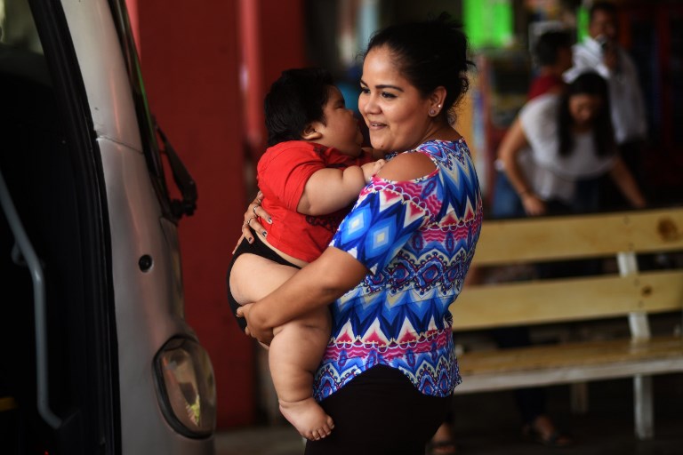 OBESE. Isabel Pantoja, 24, holds her ten-month-old baby Luis Gonzales as they wait at the bus station in Colima city where they headed for Luis' medical chek-up, in Mexico on November 9, 2017. Photo by Pedro Pardo/AFP 