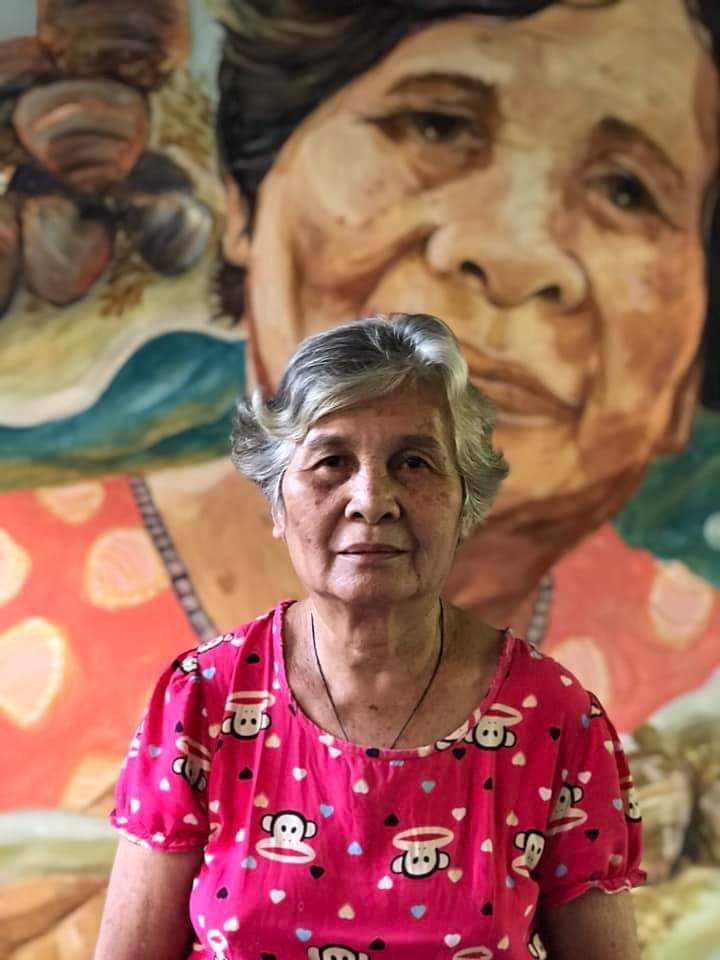 MUSE. Lola Denia, one of Barotac Viejo's oldest manuglab-as, or fishmongers, stands in front of the mural depicting her portrait inside the town's public market. The work is by Ilonggo artist Ron Matthews Espinosa. Photo by Marrz Capanang