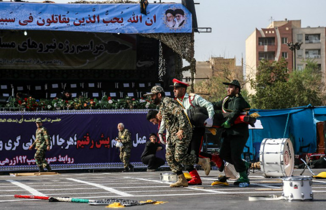 ATTACKS. This picture taken on September 22, 2018 in the southwestern Iranian city of Ahvaz shows Iranian soldiers carrying away an injured comrade at the scene of an attack on a military parade that was marking the anniversary of the outbreak of its devastating 1980-1988 war with Saddam Hussein's Iraq. Photo by Morteza Jaberian/ISNA/AFP 