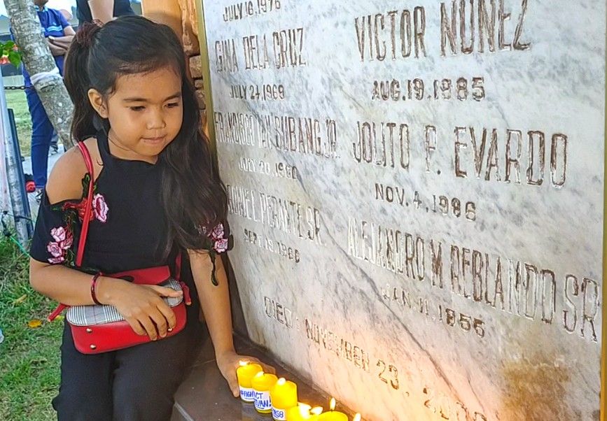 LOSS. Princess Arianne Caniban, 10 years old, lights a candle at the Forest Lake cemetery in General Santos City on November 17, 2019, where most of the Ampatuan massacre victims are buried. Photo by Lian Buan/Rappler 