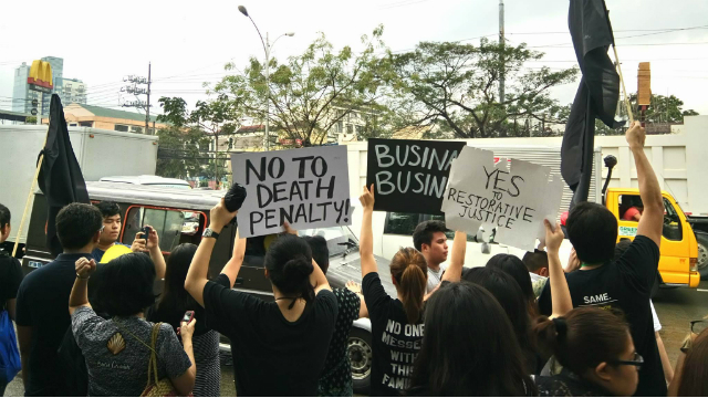 RESTORATIVE JUSTICE. Ateneo de Manila students hold placards in Gate 2.5 to convince motorists to buzz their horns in protest. Photo courtesy of Xavier Alvaran 