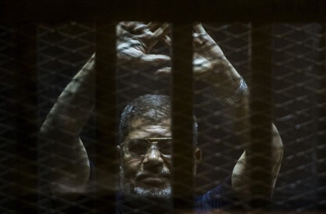 A file picture taken on June 2, 2015 shows ousted Egyptian president Mohamed Morsi gesturing from the defendants cage as he attends his trial at the police academy on the outskirts of the capital Cairo. An Egyptian appeals court has overturned a death sentence handed down against ousted Islamist president Mohamed Morsi in one of several trials since his 2013 overthrow, a judicial official said on November 15, 2016. KHALED DESOUKI / AFP 