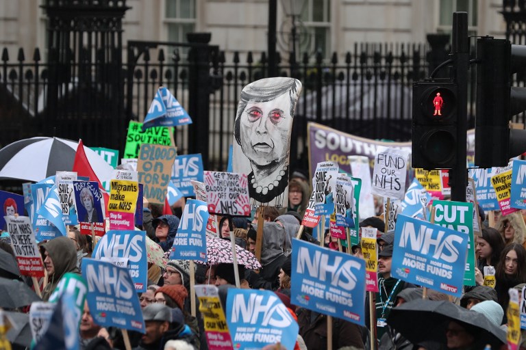 NATIONAL HEALTH SERVICE. A placard portraying Britain's Prime Minister Theresa May (C) is held by protesters during a march calling for an end to the "crisis" in the state-run National Health Service (NHS), in central London on February 3, 2018. File photo by Daniel Leal-Olivas/AFP 
