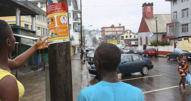 Liberians read an information poster about the prevention of contracting the Ebola virus on a street in Monrovia, Liberia, 27 July 2014. Ahmed Jallanzo/EPA
