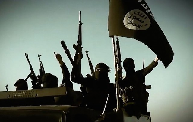 An image grab taken from a propaganda video released on March 17, 2014 by the Islamic State of Iraq and Syria (ISIS)'s al-Furqan Media allegedly shows ISIS fighters raising their weapons as they stand on a vehicle mounted with the trademark Jihadists flag at an undisclosed location in the Anbar province. File Photo by Al-Furqan Media/AFP