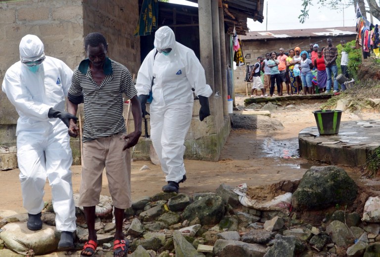 TO ISOLATION. A picture taken on August 25, 2014 in Monrovia shows nurses wearing a protective suit escorting a man infected with the Ebola virus to a hospital in Monrovia. Zoom Dosso/AFP