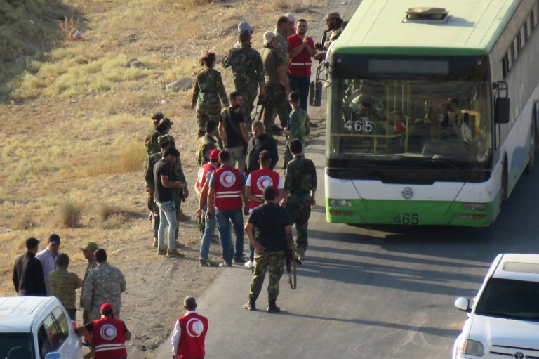 EVACUEES. Red Cross workers and government forces receive buses carrying Syrian rebel fighters and their families following their arrival in Flita on August 14, 2017. Photo by AFP 