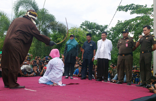 Aljogo sedang mencambuk seorang perempuan yang terbukti melanggar qanun syariat Islam tentang khalwat atau mesum di halaman Masjid Al Badar, Gampong Kota Baru, Banda Aceh, Jumat, 12 Juni. Foto oleh Nurdin Hasan/Rappler 