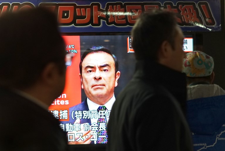 DETENTION. Pedestrians look at a television screen showing a news program featuring former Nissan chief Carlos Ghosn in Tokyo on December 21, 2018. File photo by Kazuhiro Nogi/AFP  