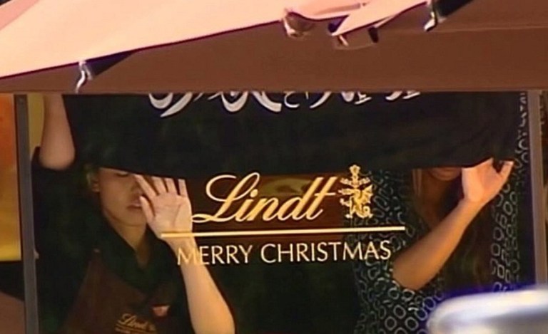 SYDNEY SIEGE. This screengrab taken from the Australian Channel Seven broadcast shows presumed hostages holding up a flag with Arabic writing inside a cafe in the central business district of Sydney on December 15, 2014. Channel Seven/AFP