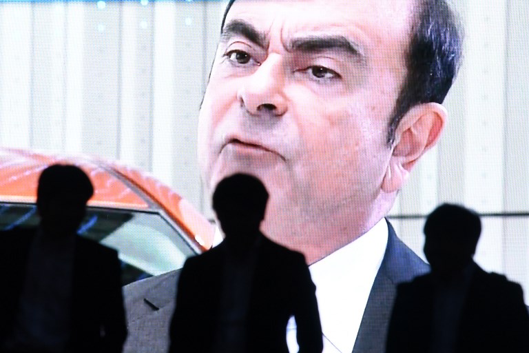 CARLOS GHOSN. Men walk past a screen showing a news program featuring Carlos Ghosn in Tokyo on November 20, 2018. File photo by Toshifumi Kitamura/AFP 
