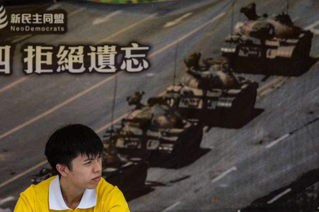 MORE KILLED? An activist sits in front of a poster of the 'Tank Man' a popular figure related to the bloody Tiananmen Square crackdown in 1989. File photo by Anthony Wallace/ AFP 