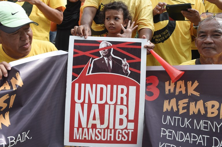 MUNDUR. Seorang anak kecil (tengah) tengah berdiri di belakang sebuah poster bertuliskan "Najib Mundur" di saat demonstrasi bersih akan melakukan aksi mereka pada Sabtu, 19 November di Ipoh, bagian timur laut Malaysia. Foto oleh Mohd Rasfan/AFP 
