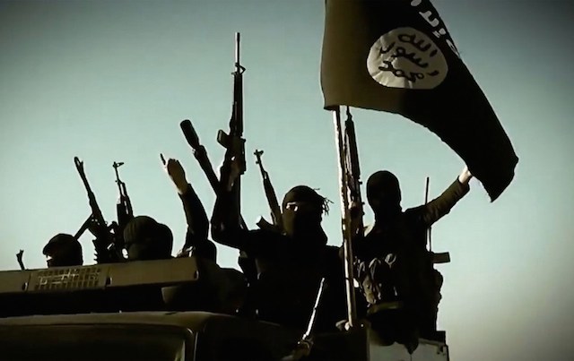 An image grab taken from a propaganda video released on March 17, 2014 by the Islamic State of Iraq and Syria (ISIS)'s al-Furqan Media allegedly shows ISIS fighters raising their weapons as they stand on a vehicle mounted with the trademark Jihadists flag at an undisclosed location in the Anbar province. Al-Furqan Media/AFP