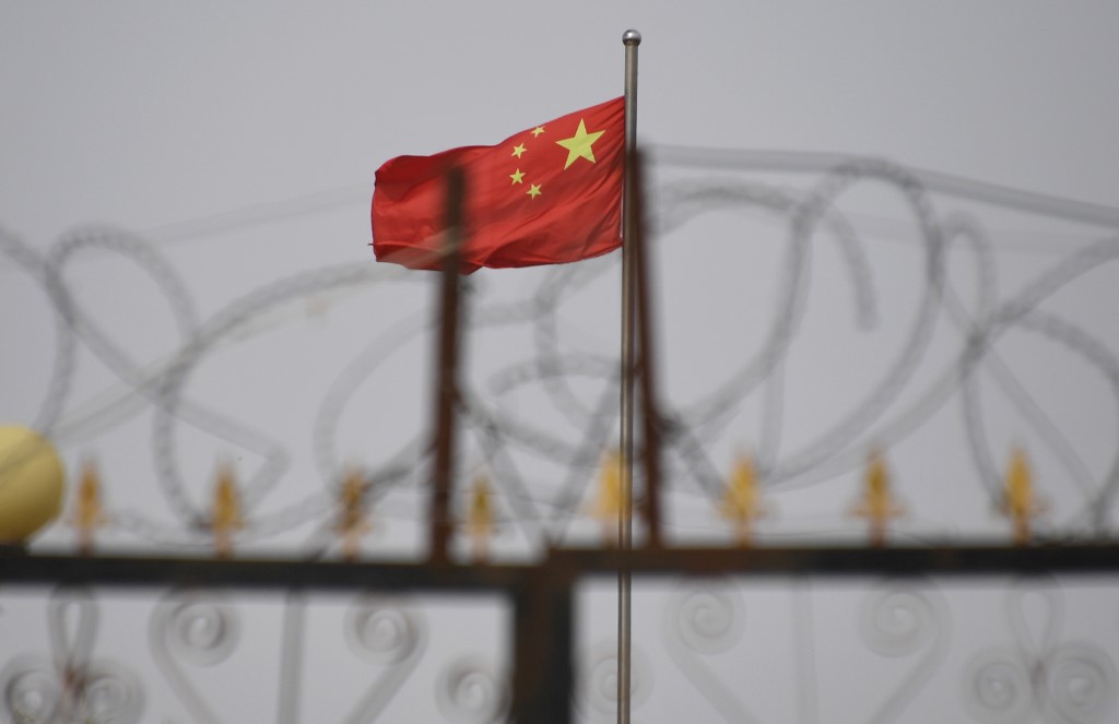 XINJIANG. This photo taken on June 4, 2019 shows the Chinese flag behind razor wire at a housing compound in Yangisar, south of Kashgar, in China's western Xinjiang region. File photo by Greg Baker/AFP 