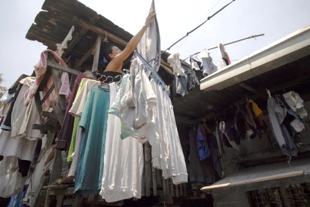 DAILY CHORE. A woman hangs laundry from a window outside her shanty in Manila. A new city ordinance bans hanging clothes outside windows and other areas that cause 'visual clutter.' File photo by Luis Liwanag/AFP   