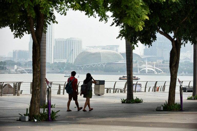 WALKING IN SINGAPORE. A couple walks along the promenade as a haze can be seen visible over the the Esplanade theatre (background) in Singapore on September 15, 2014. Photo by Rosland Rahman/AFP 