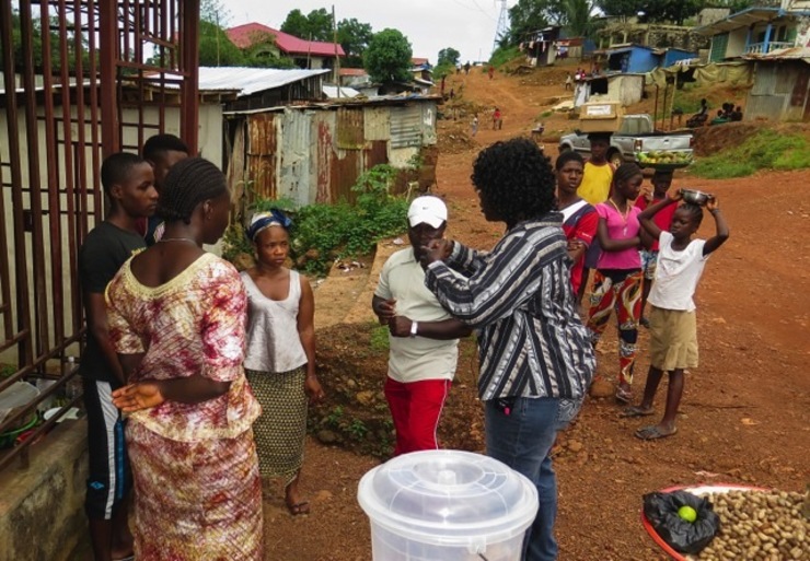 'ACCEPT SURVIVORS.' A 'Save The Children' community health team worker talks to locals on a door-to-door sensitization about Ebola at the Hill Station community west of Freetown, Sierra Leone, 08 October 2014. File photo by EPA/STR