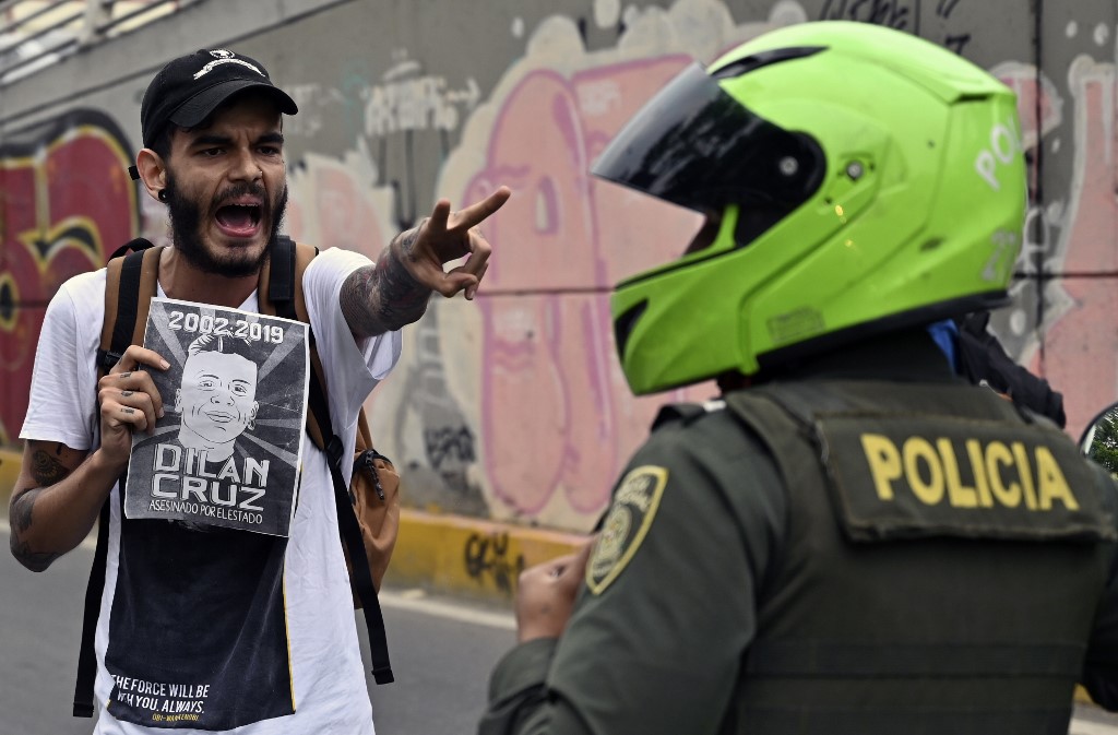 FACE-OFF. A demonstrator holding a poster of the late Dilan Cruz -who died due to injuries from a police shot- shouts at riot police during a march against the government of Colombian President Ivan Duque during a national strike in Cali on November 27, 2019. Photo by Luis Robayo/AFP  