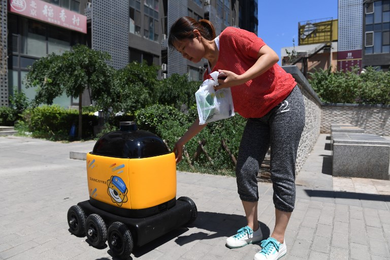 ROBOT DELIVERY. A woman picks up groceries delivered by a Zhen Robotics delivery robot at a residential compound during a demonstration of the robot in Beijing. Photo by Greg Baker/AFP 