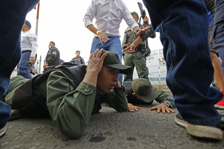 CRISIS. Two Venezuelan soldiers lie on the ground as they are detained by Colombian police after driving into Colombia in an armor car from the Venezuelan side of Simon Bolivar International bridge in Cucuta on February 23, 2019. Photo by Schneyder Mendoza/AFP 