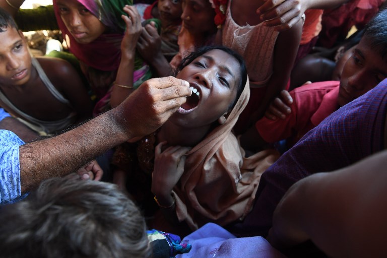 LOST CHILDHOOD. A Rohingya refugee receives an oral cholera vaccine from a Bangladeshi volunteer at the Thankhali refugee camp in Ukhia district on October 10, 2017. 
Photo by Indranil Mukherjee/AFP 
