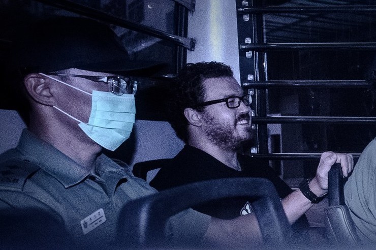 British banker Rurik Jutting, charged with the grisly murders of two women, smiles as he sits in a prison van leaving the eastern court in Hong Kong on November 10, 2014. Philippe Lopez/AFP