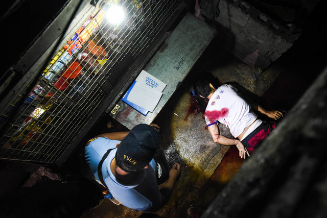 DRUG WAR CASUALTY. A policeman checks a drug suspect killed in an operation. File photo by Alecs Ongcal/Rappler  