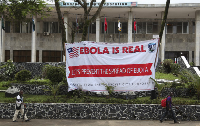 EBOLA IS REAL. Liberian men walk past an Ebola sentization banner at the Monrovia City Hall in Liberia, July 31, 2014. File photo by Ahmed Jallanzo/EPA