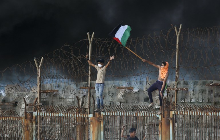 DEFIANT. Palestinian protestors place their national flag on a metal structure during a demonstration on the beach near the maritime border with Israel, in the northern Gaza Strip, on October 8, 2018. Photo by
Said Khatib/AFP  