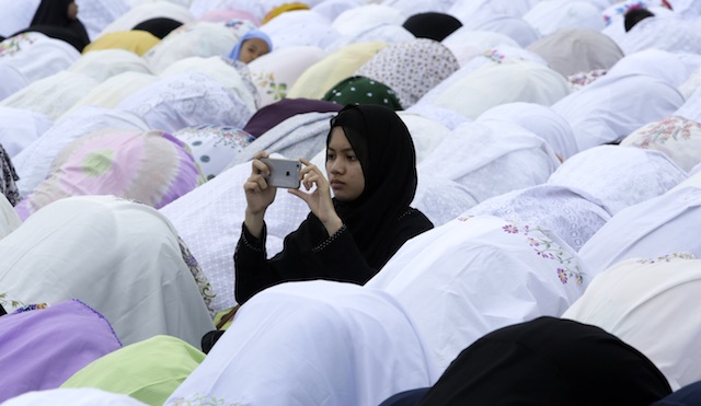 ISLAM. An Indonesian Muslim woman takes a picture of her fellows during a mass prayer marking the Eid Al-Adha celebrations in Banda Aceh, Indonesia. File photo from EPA  