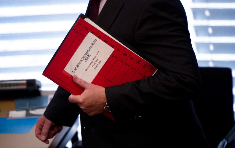 SURVEILLANCE. A picture taken on April 3, 2014 in Berlin shows a man carrying files before the first session of the committee of inquiry investigating into the possible data surveillance by British and the US National Security Agency (NSA). Photo by Daniel Naupold/dpa/AFP 