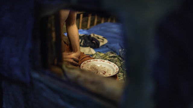 SHACKLED. Ikram, a man with a psychosocial disability, eats his dinner in a shed outside the family home where he has been locked up. His family gives him food and water through a small hole in the shed. Photo by Human Rights Watch  