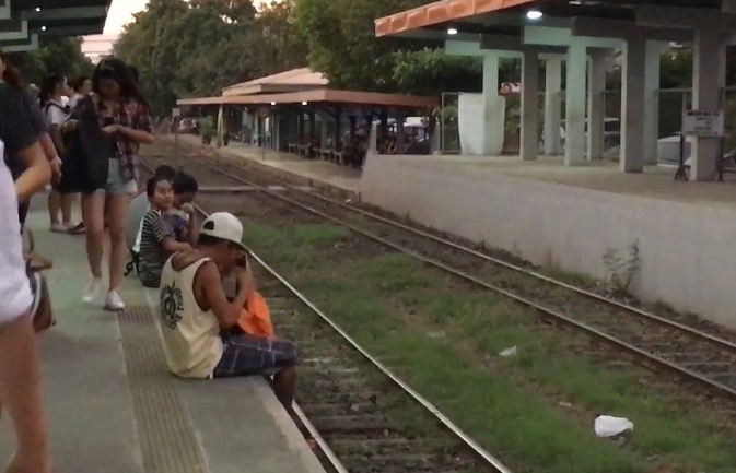 WAITING TIME. Passengers sit on the edge of the station platform while waiting for the train to arrive. Photo by Camille Elemia/Rappler   