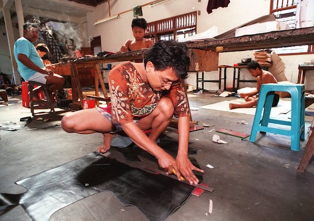 Seorang pekerja di Sidoarjo, Jawa Timur, membuat replika sebuah merk ternama untuk dijual kembali di pasar lokal. Foto oleh AFP 