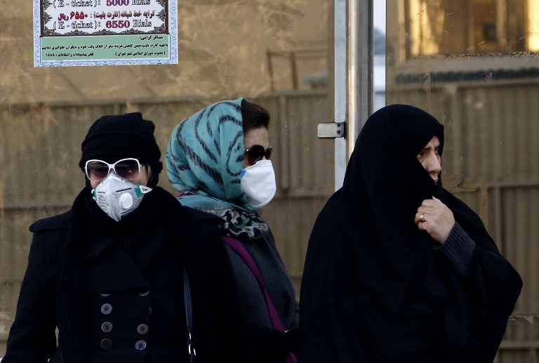 MASKED. Iranian women wearing face masks wait at a bus stop as winter's heavy pollution has hit new highs in the capital Tehran, on December 17, 2017. Photo by Atta Kenare/AFP 
