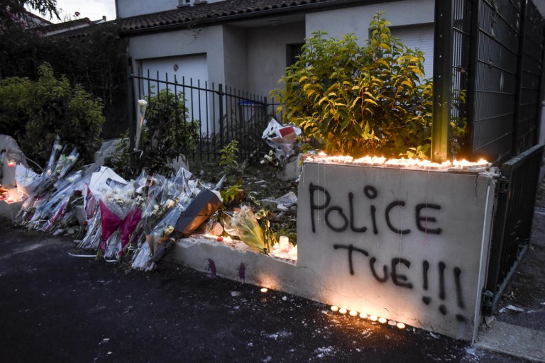 'JUSTICE FOR ABOU'. Candles and flowers are placed near the words 'police kill' spray painted on the wall reportedly damaged by the car of the young man who was shot dead by an officer during a police check on the night of July 3, in the Le Breil neighborhood of Nantes, western France, on July 6, 2018. Photo by Sebastien Salom Gomis/AFP 