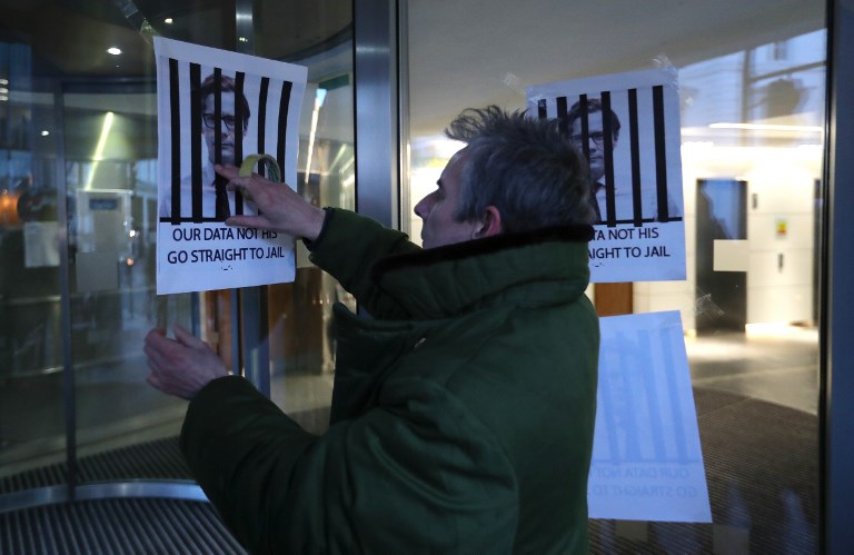 CAMBRIDGE ANALYTICA. A man fixes posters depicting Cambridge Analytica's CEO Alexander Nix behind bars, with the slogan "Our Data Not His. Go Straight To Jail" to the entrance of the company's offices in central London on March 20, 2018. Photo by Daniel Leal-Olivas/AFP 