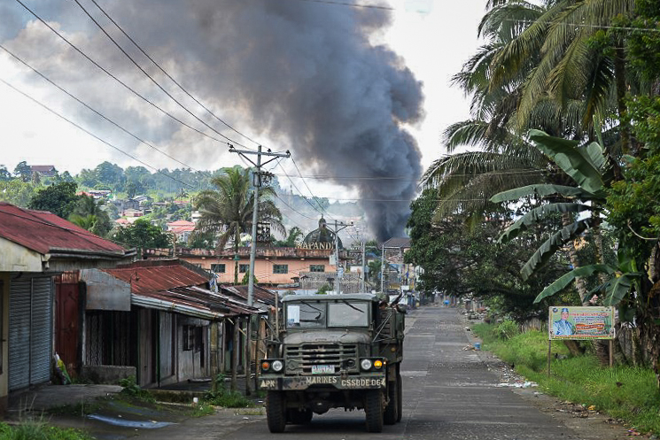 URBAN WARFARE. A Philippine Marines truck speeds away as black smoke billows from burning houses after military helicopters fired rockets at militant positions in Marawi on May 30, 2017. Photo by Ted Aljibe/AFP 