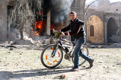 'CATASTROPHIC.' A Syrian youth pushes his bicycle past a burning house on November 19, 2016 following a reported air strike on Aleppo's rebel-held neighborhood of Bab al-Nayrab. Photo by Ameer Alhalbi/AFP 