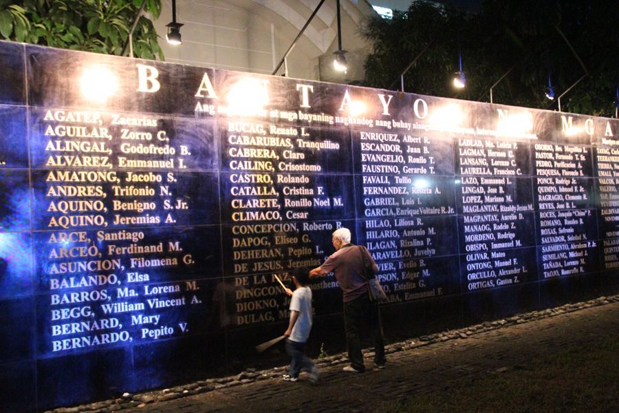 WALL OF REMEMBRANCE. An elderly man teaches a child about the significance of the Wall of Remembrance, where 268 names of martial law martyrs are inscribed in black granite. Photo by Rome Jorge/Rappler  