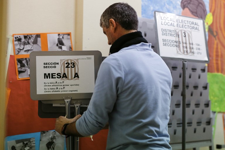 ELECTIONS. A man holds information placards for the Catalan regional election, during a polling station setup at the 'Prat de la Mata' school on the eve of the voting day in L'Hospitalet del Llobregat on December 20, 2017. Photo by Pau Barrena/AFP 